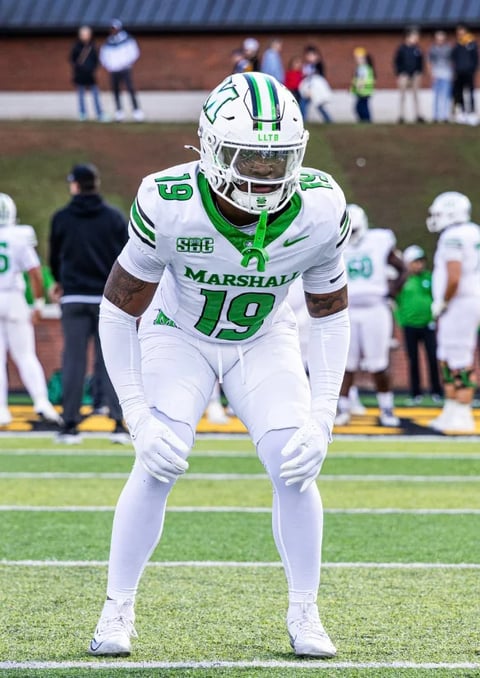 Marshall football player number 19 in white and green uniform in defensive stance on field during game